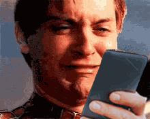 Spider-Man looks sadly down at a phone in a dramatic close-up.