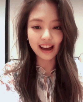 Jennie smiles toward the camera in a bright vertical selfie-style clip.