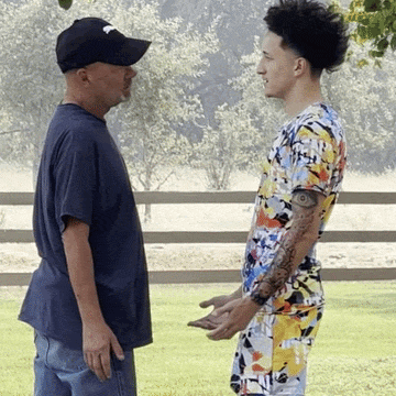 a man in a black hat stands next to a young man in a floral shirt