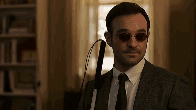 a man in a suit and tie is holding a cane .