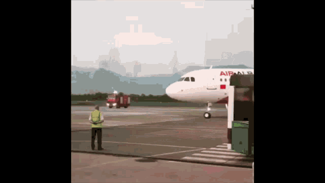 a man in a yellow vest stands in front of an airplane that says airalp