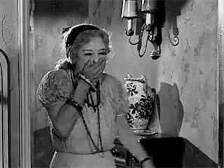 a black and white photo of a woman covering her mouth with her hands .