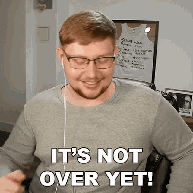 a man wearing glasses and ear buds says " it 's not over yet "