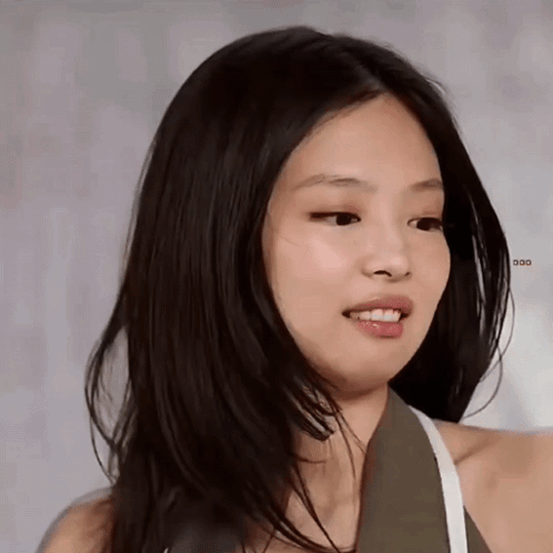 Jennie smiles softly during an interview against a pale background.