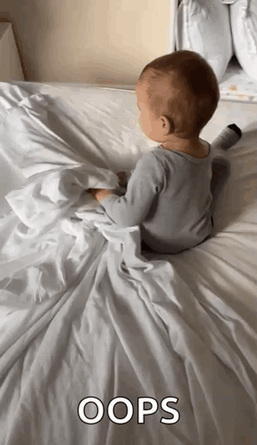 A baby sits turned away on a rumpled bed beneath the caption “OOPS.”