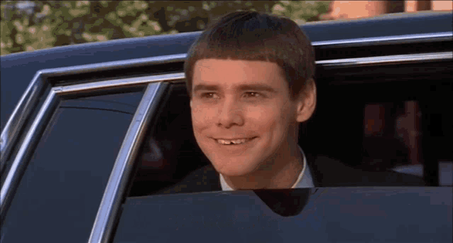 a man in a suit is sitting in a limousine and smiling .