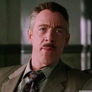 A mustached man looks seriously ahead in a film-like scene.