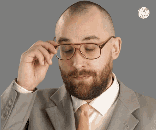 a man in a suit adjusts his glasses with a cat on the bottom right