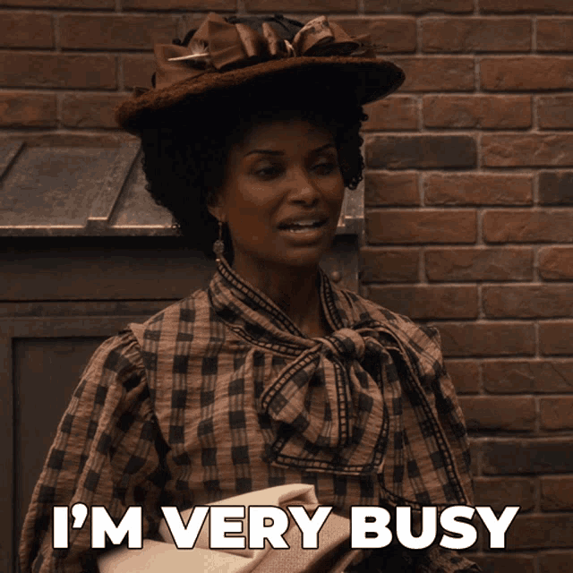 a woman says i 'm very busy while wearing a hat