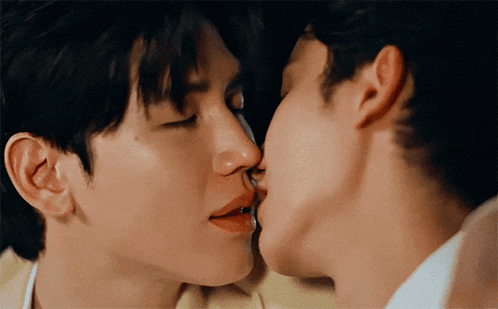 Two men share a close kiss in a dramatic scene.