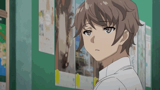 a boy in a white shirt and tie stands in front of a wall with posters on it