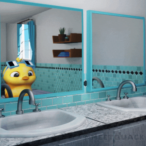 a bathroom with two sinks and a duck wearing goggles in the mirror