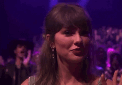 a woman is smiling in front of a crowd of people in a purple room .