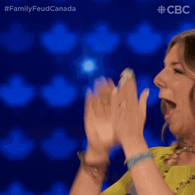 A woman claps her hands together on the Family Feud Canada set.