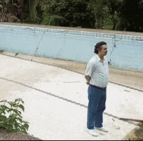 A man stands alone beside an empty pool, waiting pensively.
