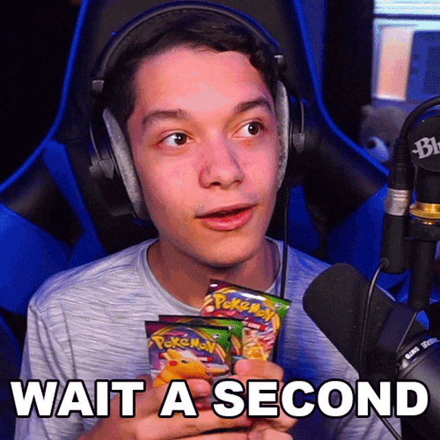 a young man wearing headphones is holding a pack of pokemon cards and says wait a second