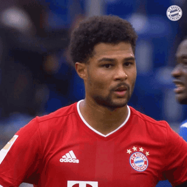 a soccer player wearing a red adidas jersey looks to the side