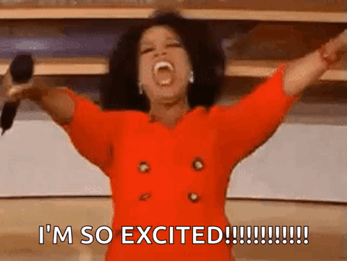 A woman in red throws her arms wide and says “I’M SO EXCITED!!!!!!!!!!!!”