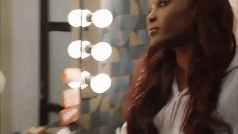 a woman with red hair is looking at herself in the mirror .
