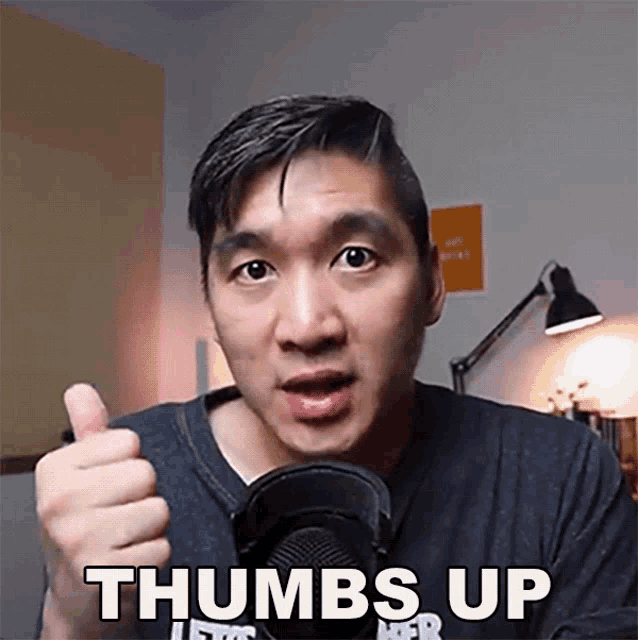 a man is giving a thumbs up in front of a microphone
