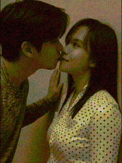 A couple kisses closely, with one person touching the other's face.