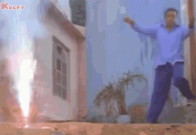 a man in a blue shirt is dancing in front of a firework display .