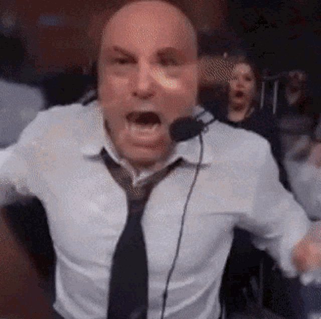 Joe Rogan reacts with a shocked open mouth at a microphone.