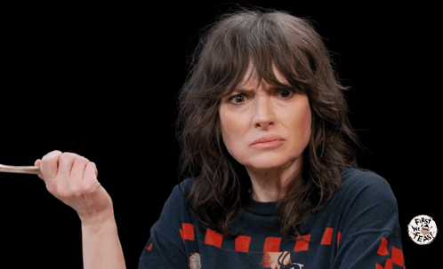 Winona Ryder on Hot Ones raises a hand in a questioning shrug.