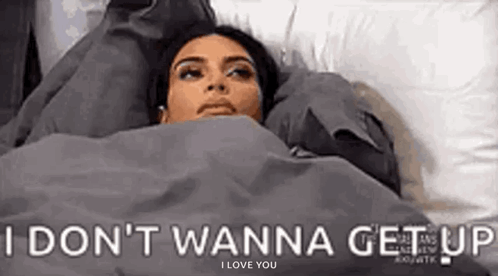 A person lies in bed under the caption “I DON’T WANNA GET UP.”