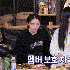 two women are sitting at a table with food and one has a sweatshirt that says glott