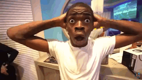 A man holds both hands behind his head in exaggerated shock.