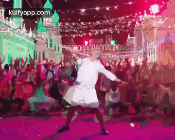 a man is dancing on a stage in front of a crowd .