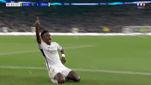 a soccer player is kneeling on the field with his arms up