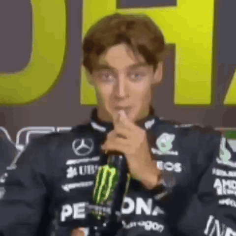 a man is holding a bottle of monster energy drink and making a funny face while talking into a microphone .