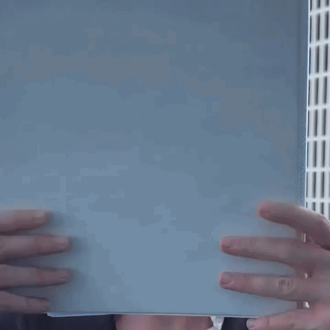 a man with curly hair is peeking over a white box