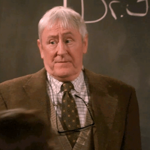 an older man stands in front of a blackboard that says dr.