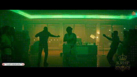 a group of people are dancing in a dark room with green lights behind them .