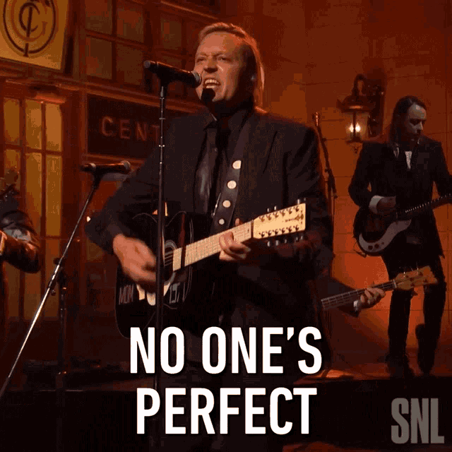 a man singing into a microphone while playing a guitar with the words no one 's perfect below him