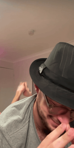 Man in a hat claps his feet together in disbelief.