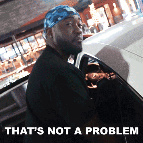 a man with a bandana on his head is standing next to a car with the words that 's not a problem written below him