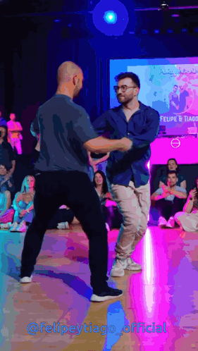 two men are dancing in front of a screen that says felipe tiago