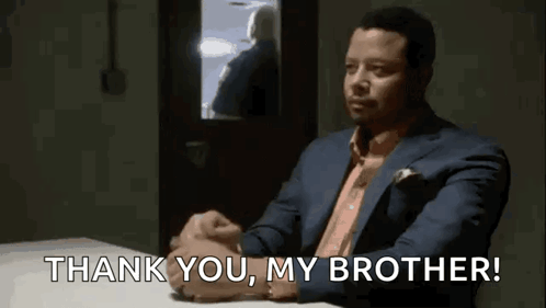 a man in a suit is sitting at a table and says `` thank you , my brother '' .