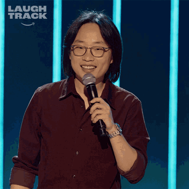 a man is holding a microphone in front of a laugh track logo