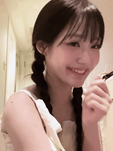 A smiling young woman holds her hand near her face shyly.