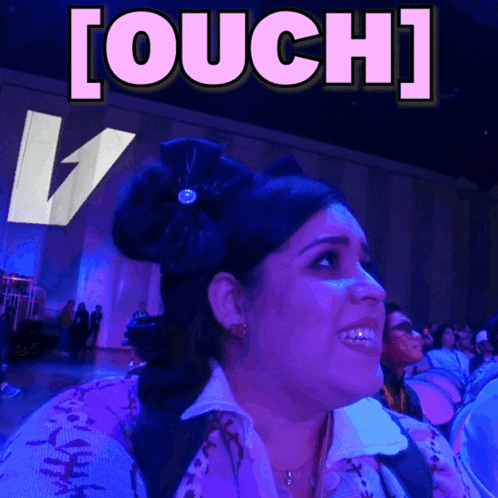 A woman at an event looks shocked beneath a large “[OUCH]” caption.