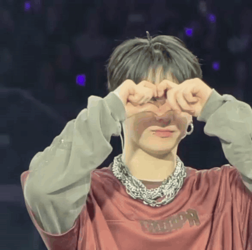 A performer makes heart shapes around his eyes with both hands onstage.