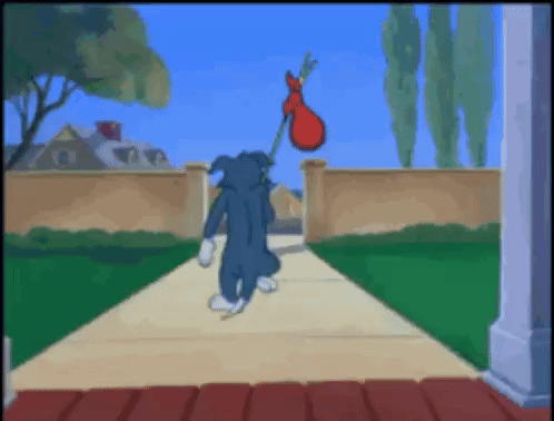 Tom walks away down a path in a Tom and Jerry cartoon scene.