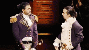 two men in military uniforms are standing next to each other on a stage and talking to each other .