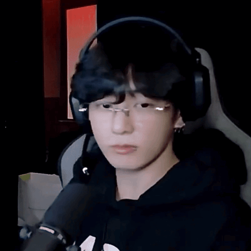 A streamer in headphones looks down beside a microphone.