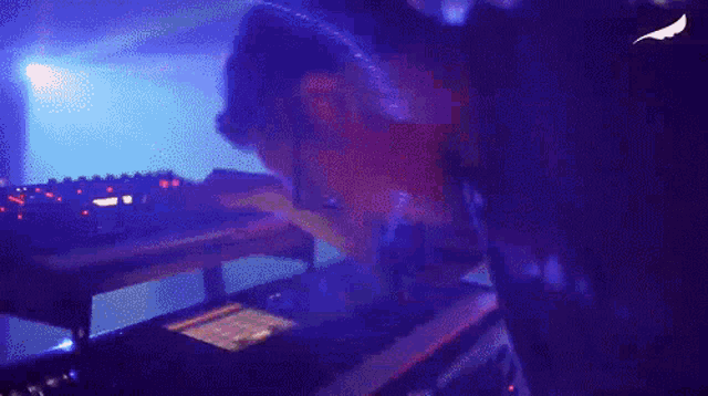 a person is playing a keyboard in a dark room with purple lights
